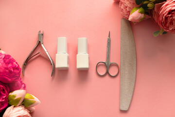 Obraz na płótnie Canvas A set of manicure tools and accessories on a pink background with flowers. Nail care. Top view, flat lay. Copy space. Women's Day. March 8