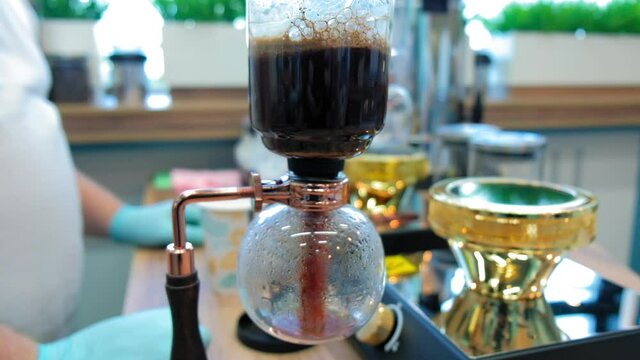 Beautiful coffee americano makes a barista in a gabe siphon in a cafe close-up, general plan