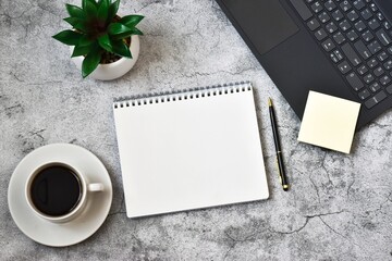 Notepad, laptop with cup coffee and pen on concrete grey background. Workplace. copy space, flat lay. Concept business and finance.