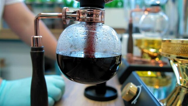 Beautiful coffee americano makes a barista in a gabe siphon in a cafe close-up, general plan