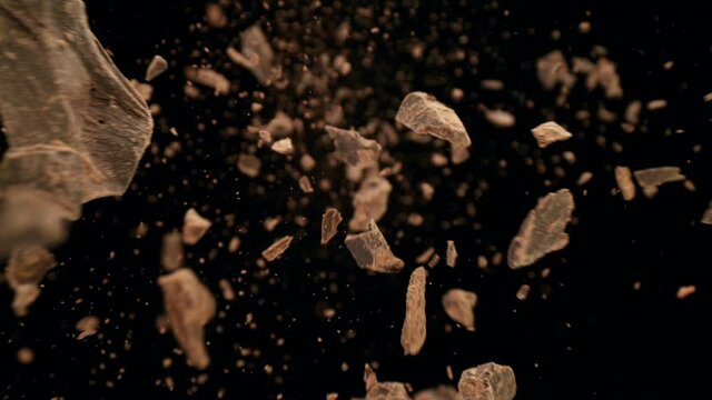 Super slow motion of falling group of raw chocolate pieces on black background. Filmed on high speed cinema camera, 1000fps.