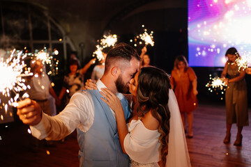 newlyweds with sparklers in night say goodbye to guests in the restaurant