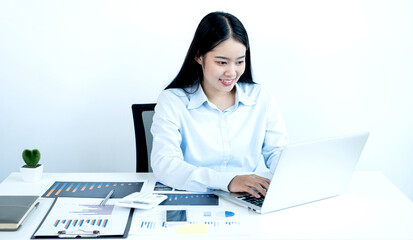 Asian female accountant sits at their desks and calculates financial graphs showing results about their investments, plan a successful business growth process