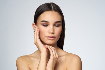 Obraz premium Woman with long hair bared shoulders clean skin body care light background