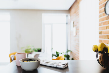 Pink coffee cup, bowl with chopped fruits and blueberries, spoon in kitchen