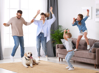 Playful family dancing in living room with dog