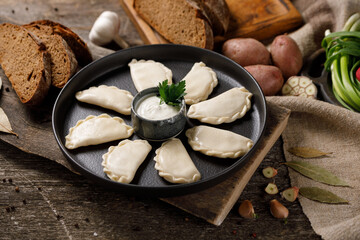 Appetizing traditional Russian dumplings, hand-made with potatoes. Still life on a wooden board. Close-up.