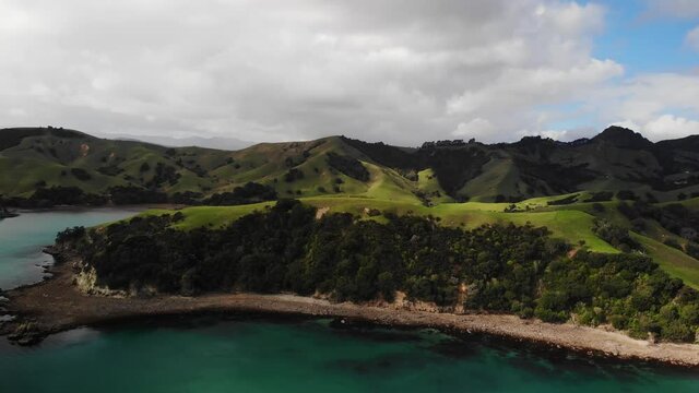 Aerial view of Wilsons Bay surrounded by grassy mountains kereta coromandel new zealand, orbit