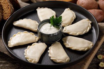 Appetizing traditional Russian dumplings, hand-made with potatoes. Still life on a wooden board. Close-up.