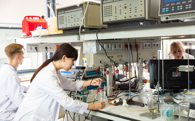 Positive Chinese female scientist near laboratory equipment at biochemical lab