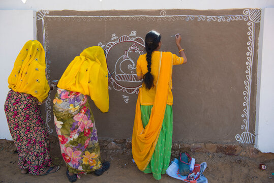 Pushkar / India 27 October 2017 Traditional rajasthani Women doing decorative painting on the wall for the Pushkar Camel Fair at Pushkar in Rajasthan India