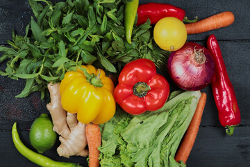 Peppers, onion, chili, lime, carrots, ginger, lettuce on the dark background