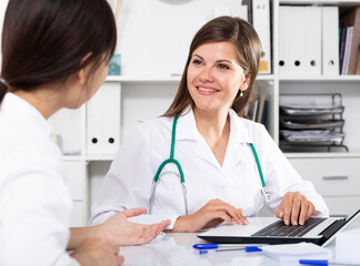 Young confident female doctor consulting woman patient in medical office