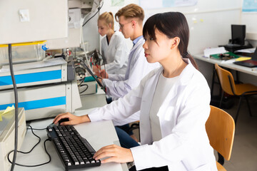 Attentive Caucasian and Asian students engaged in research at chemical lab