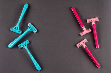 Red plastic razors against blue ones on a gray background.