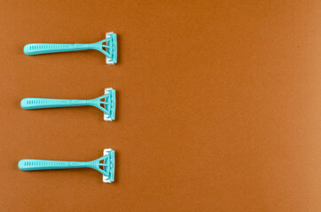 Blue plastic razors on a brown background.