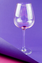 Empty dirty wine glass on blue and pink background.