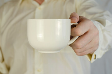 Adult Man presents a large white mug.