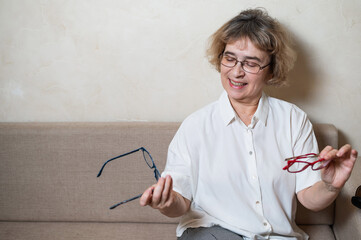 An elderly Caucasian woman chooses glasses from her home collection