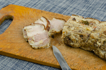 Traditional Ukrainian dish. Baked pork belly with spices on a wooden cutting board.