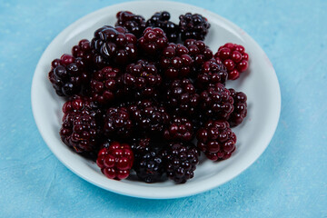 A bowl of blackberries on the blue background