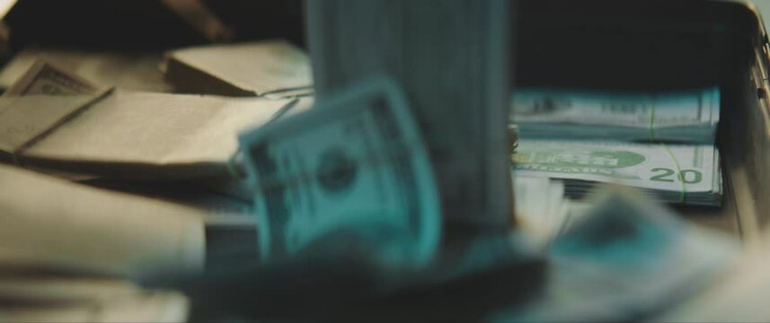 US Dollar banknotes falling into a suitcase full of money in slow motion.