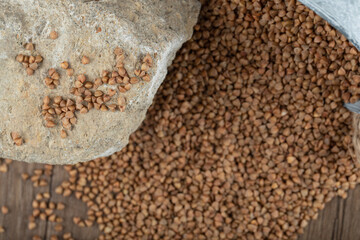 Uncooked buckwheat out of metal bucket on wooden table