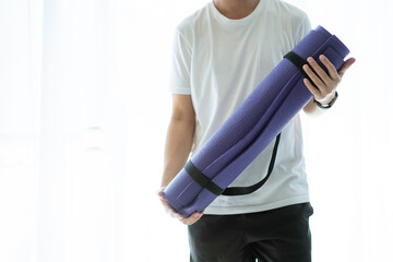 Fototapeta premium Unrecognizable Asian young man carrying a roll of yoga mat.