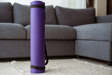 Rolled purple yoga exercise mat on the floor