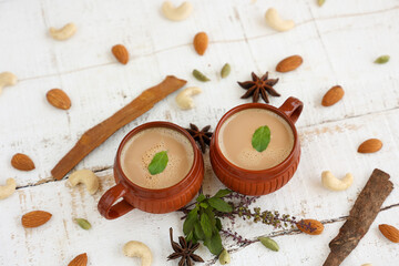 Top view of Indian herbal Masala Chai or traditional beverage tea with milk and spices Kerala India. Two cups of organic ayurvedic or herbal drink India, good in winter for immunity boosting.