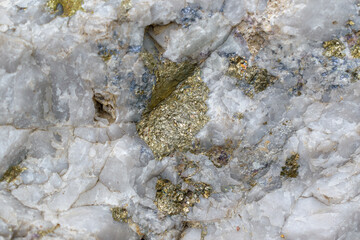 Surface of molybdenite ore. Mineral composition: molybdenite, chalcopyrite, pyrite, quartz. Shiny scales and splashes of golden color. Sorskoe deposit, Republic of Khakassia. Selective focus.