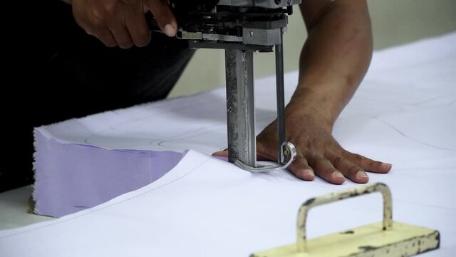 Factory worker cutting of fabric in factory. Used the razor machine for cutting fabrics in mass production.