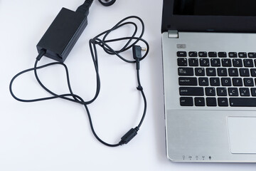 Messy charging cable adapter of laptop computer on white background