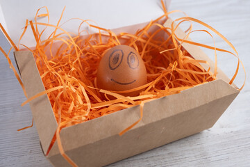 Smiling egg in a cardboard box.
