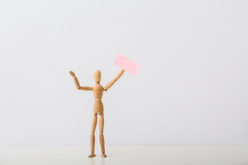 Wooden mannequin with blank placard on light background