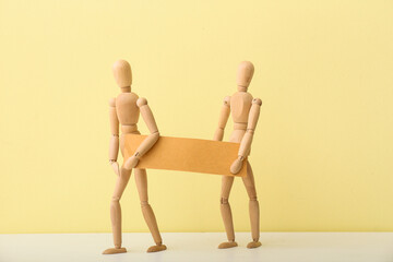 Wooden mannequins with blank poster on color background
