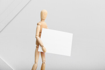 Wooden mannequin with blank poster on light background