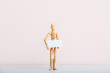 Wooden mannequin with blank poster on color background