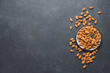 Bowl with healthy almonds on dark background