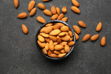 Bowl with healthy almonds on dark background