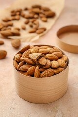 Box with healthy almonds on color background