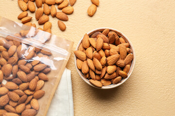 Bowl of tasty almonds on color background