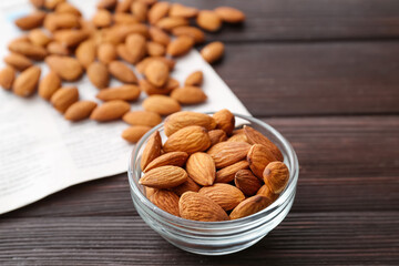 Bowl with healthy almonds on wooden background
