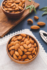 Bowls of healthy almonds on color background