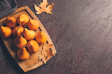 Board with fresh ripe pears on dark background