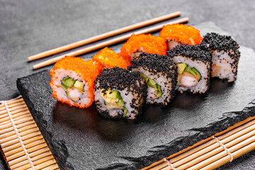 Golden dragon sushi roll with crab, salmon, cucumber, sesame seeds and cream cheese over black backgraund. Top view