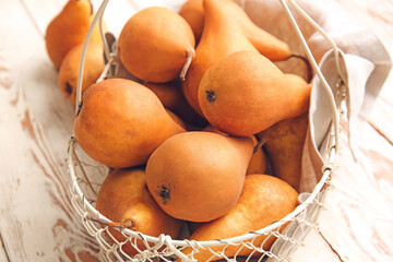 Basket with fresh ripe pears on wooden background