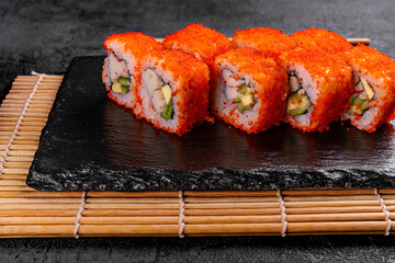 Golden dragon sushi roll with crab, salmon, cucumber, sesame seeds and cream cheese over black backgraund. Top view