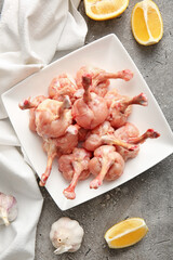 Plate with raw chicken lollipops on grey background