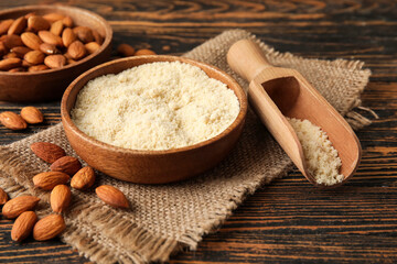 Bowl and scoop with almond flour on wooden background